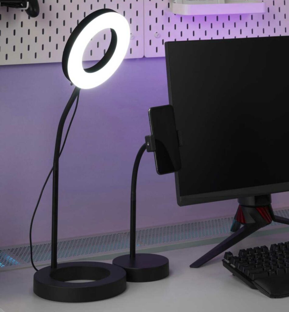 Imagem de uma mesa com a luminária Ring Light ROG E IKEA à esquerda e computador preto do lado oposto.