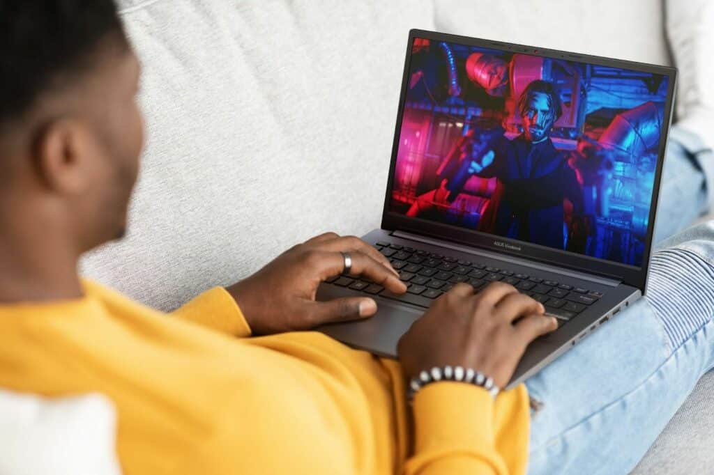 Homem usando um notebook com IA e assistindo a uma cena colorida na tela.