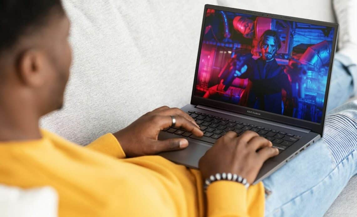 Homem usando um notebook com IA e assistindo a uma cena colorida na tela.