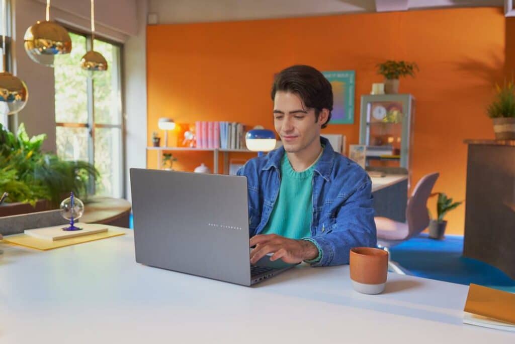 Jovem usando um notebook com IA, destacando tecnologia avançada em um ambiente de escritório moderno e colorido.