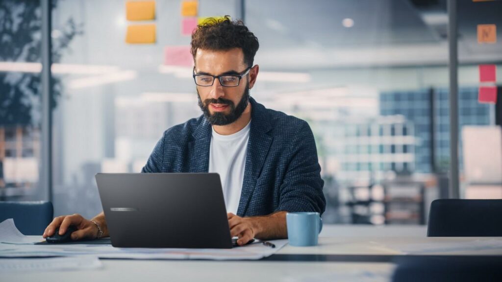 Profissional usando um notebook corporativo em escritório moderno, destacando produtividade e tecnologia.