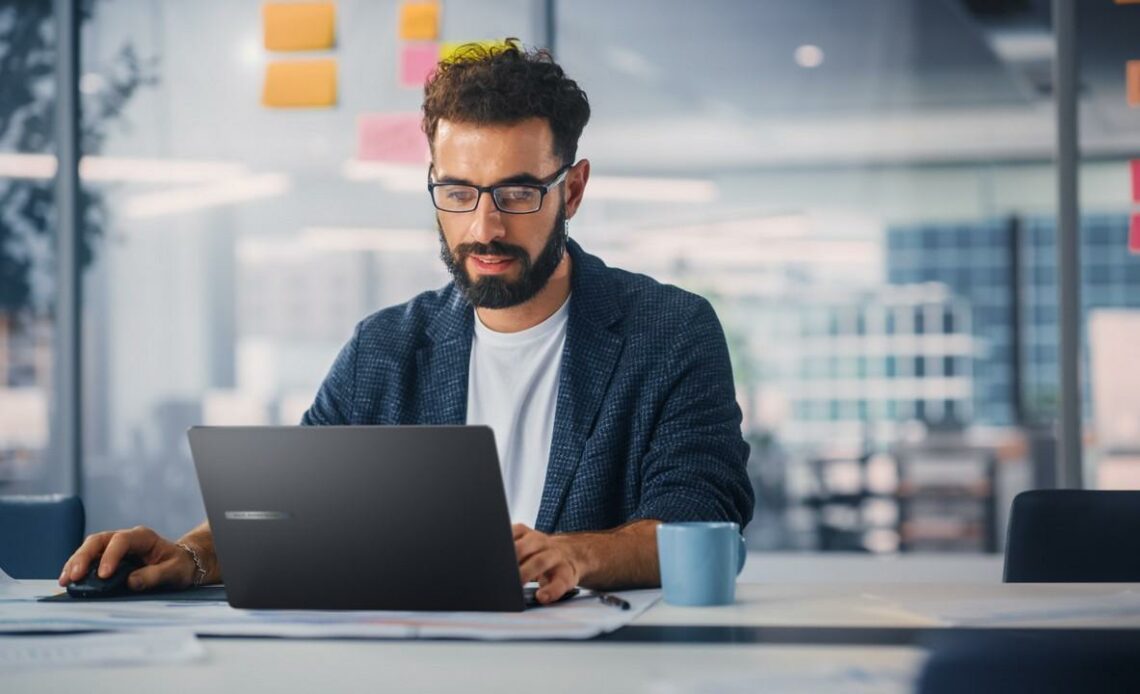Profissional usando um notebook corporativo em escritório moderno, destacando produtividade e tecnologia.